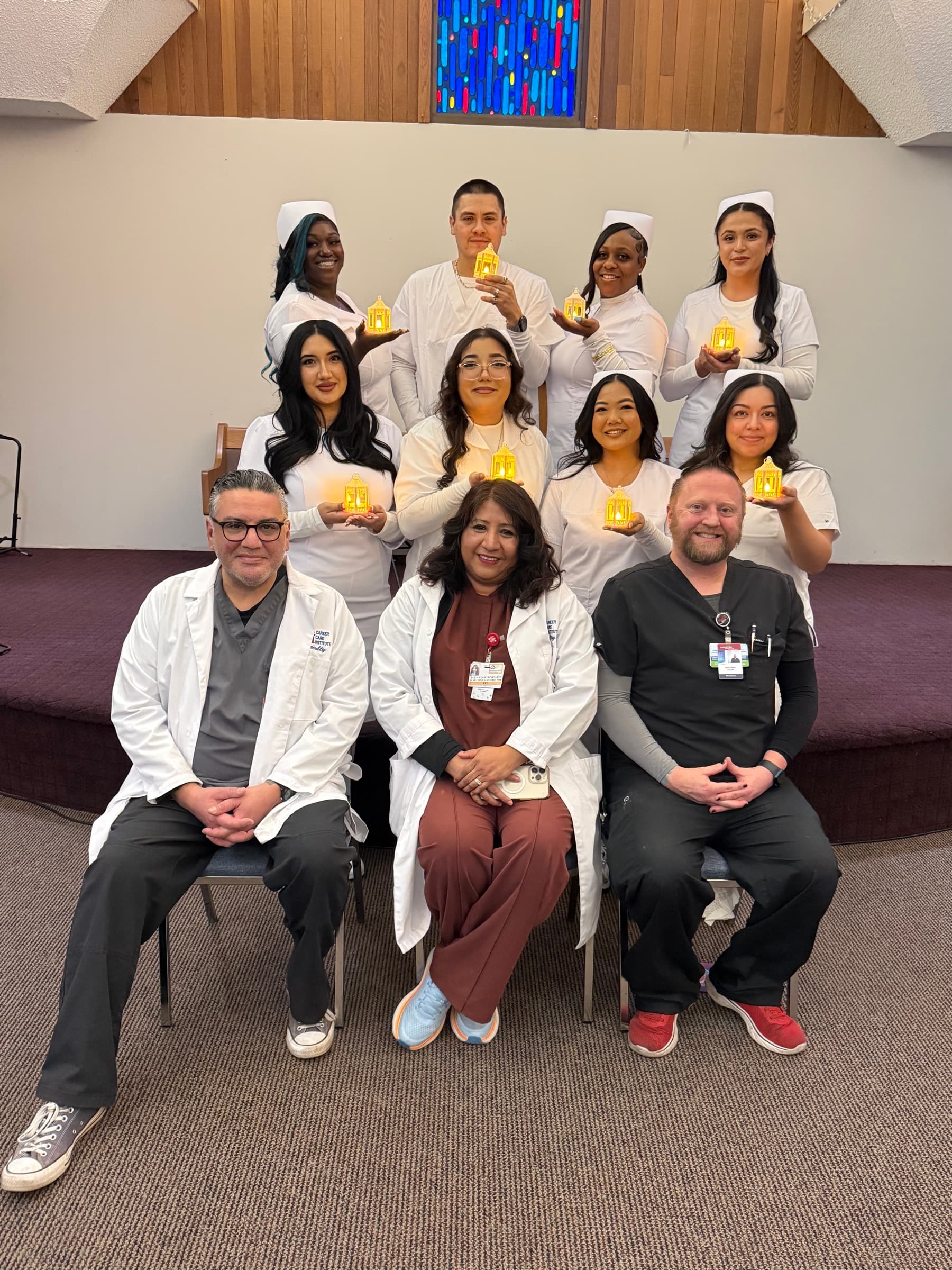 A CCI nursing cohort and instructors posing together with ceremonial lamps.
