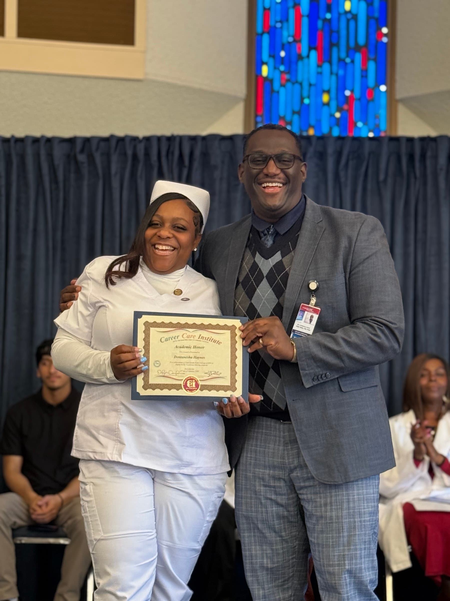 A smiling CCI nursing student receiving an academic honor certificate.