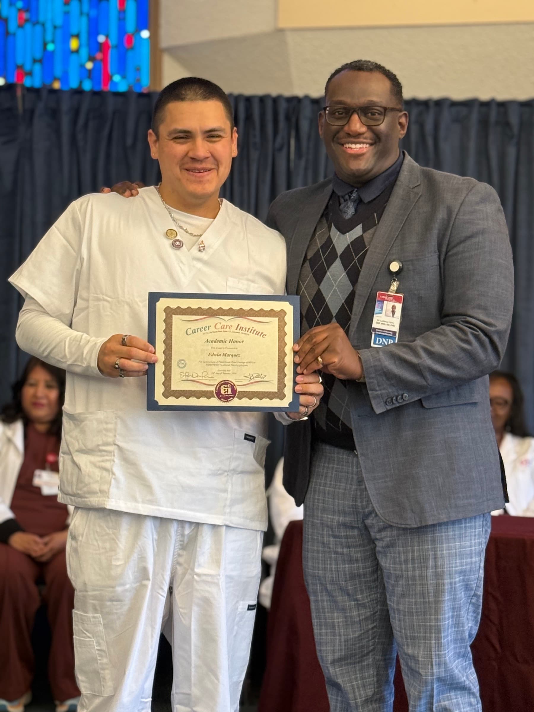 A CCI nursing student holding an academic honor certificate beside an instructor.