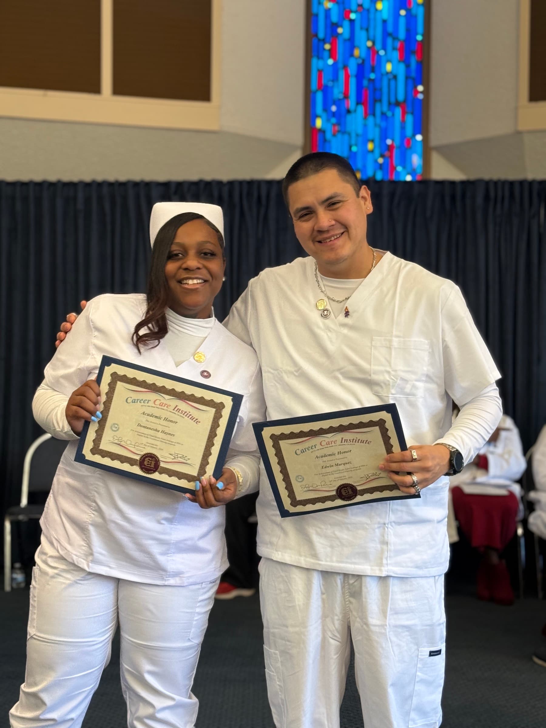 Two CCI nursing students holding academic honor certificates together.