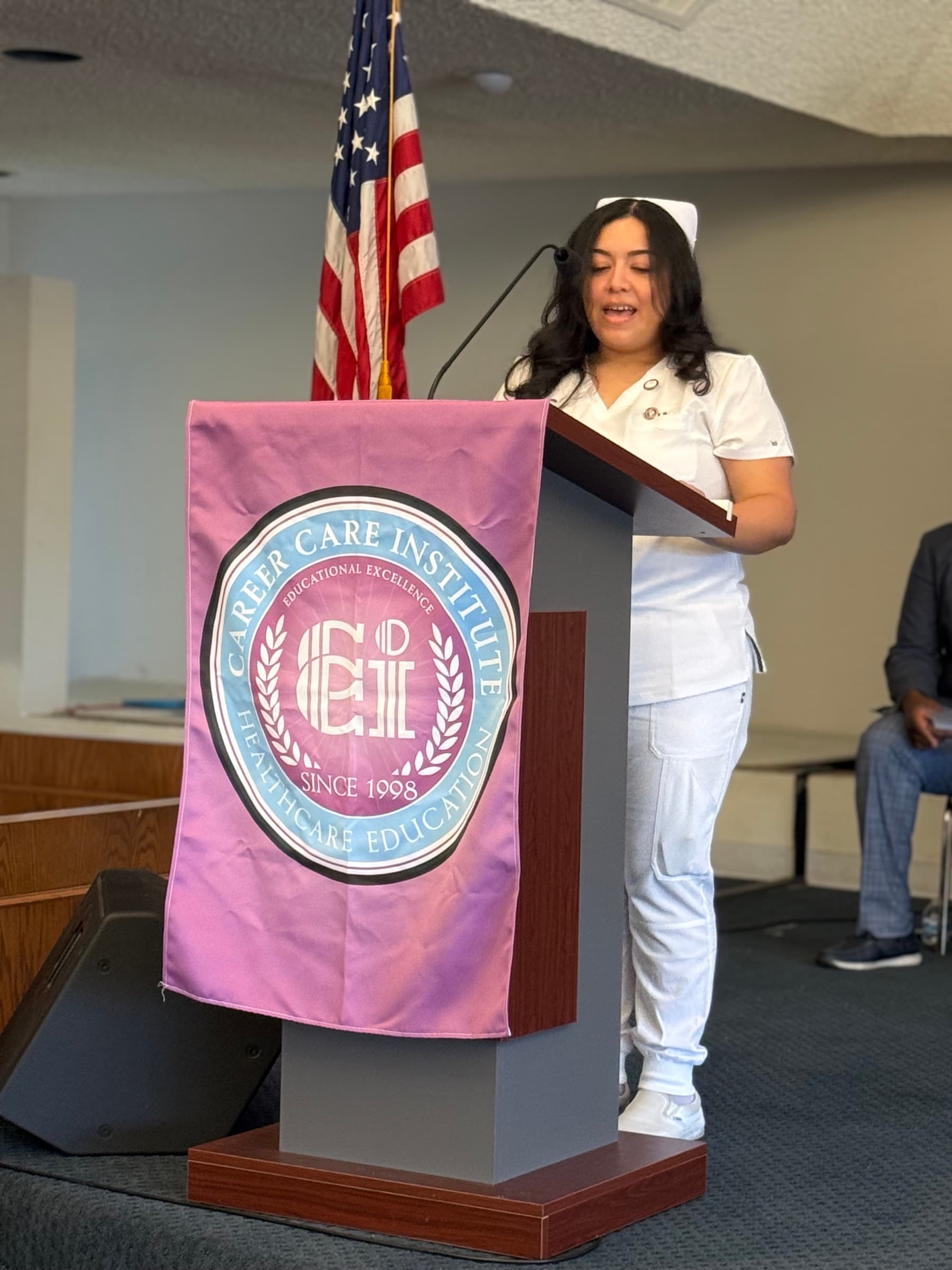 A CCI nursing student speaking from a podium during a pinning ceremony.