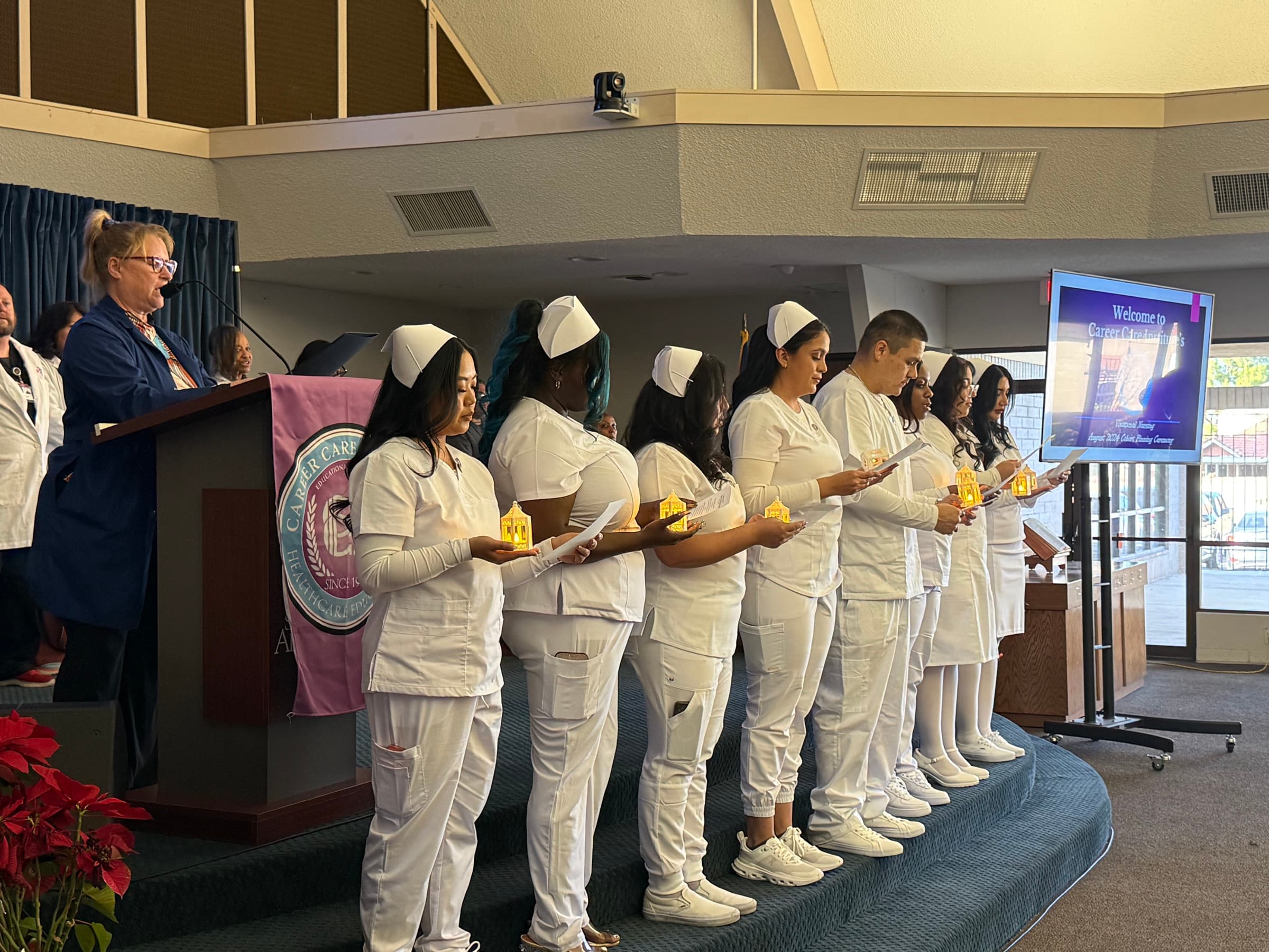 CCI nursing students standing together with ceremonial lamps during a pinning ceremony.