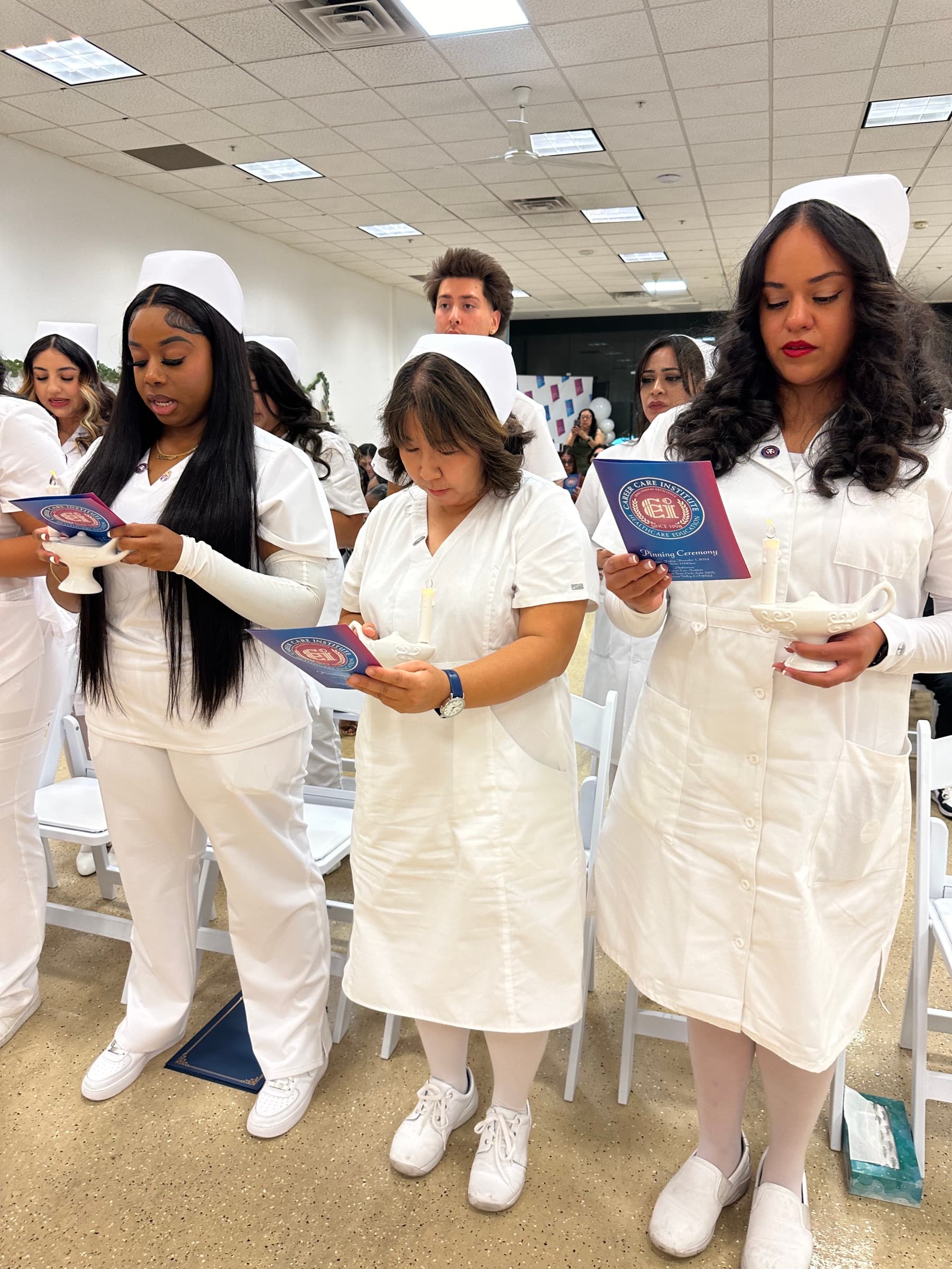 CCI nursing students holding ceremonial lamps and reading their pinning programs.