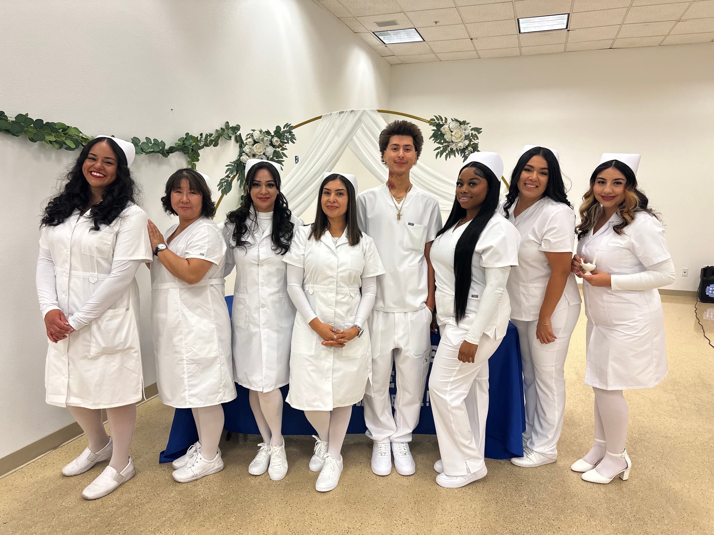 CCI nursing students standing together in white uniforms in a campus learning space.