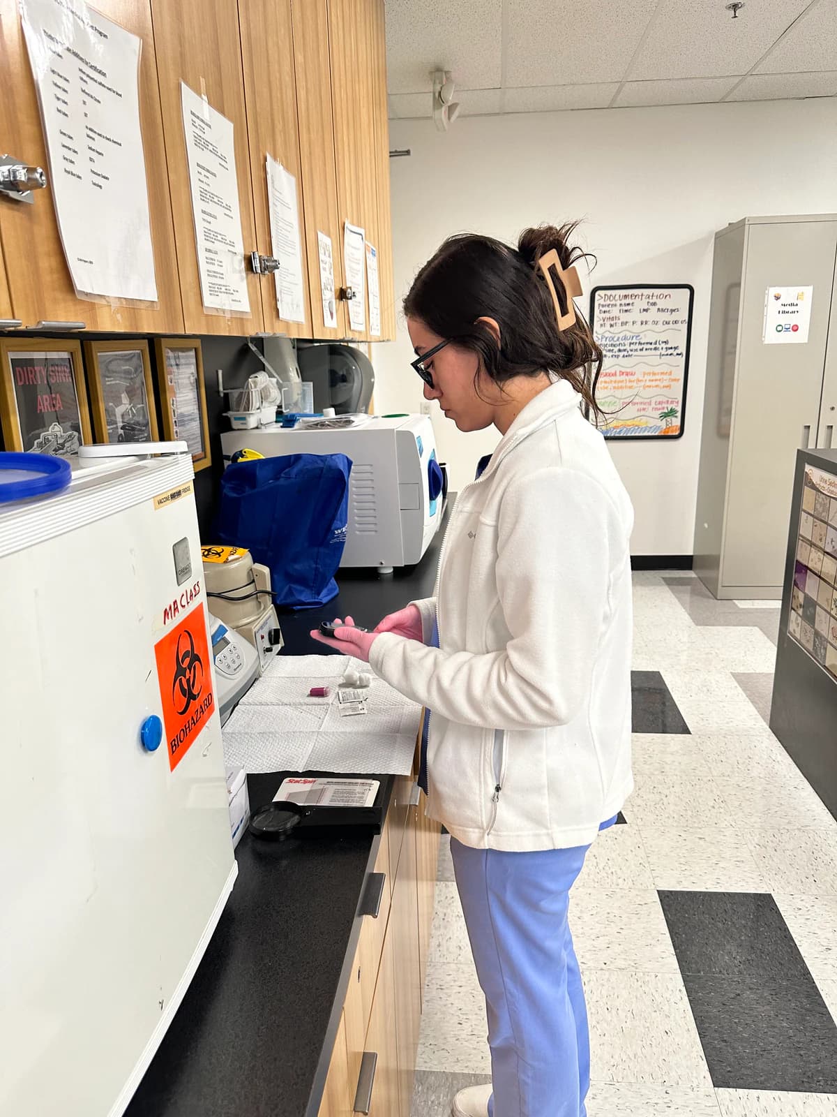 A Medical Assisting student prepares supplies at a training-lab counter.
