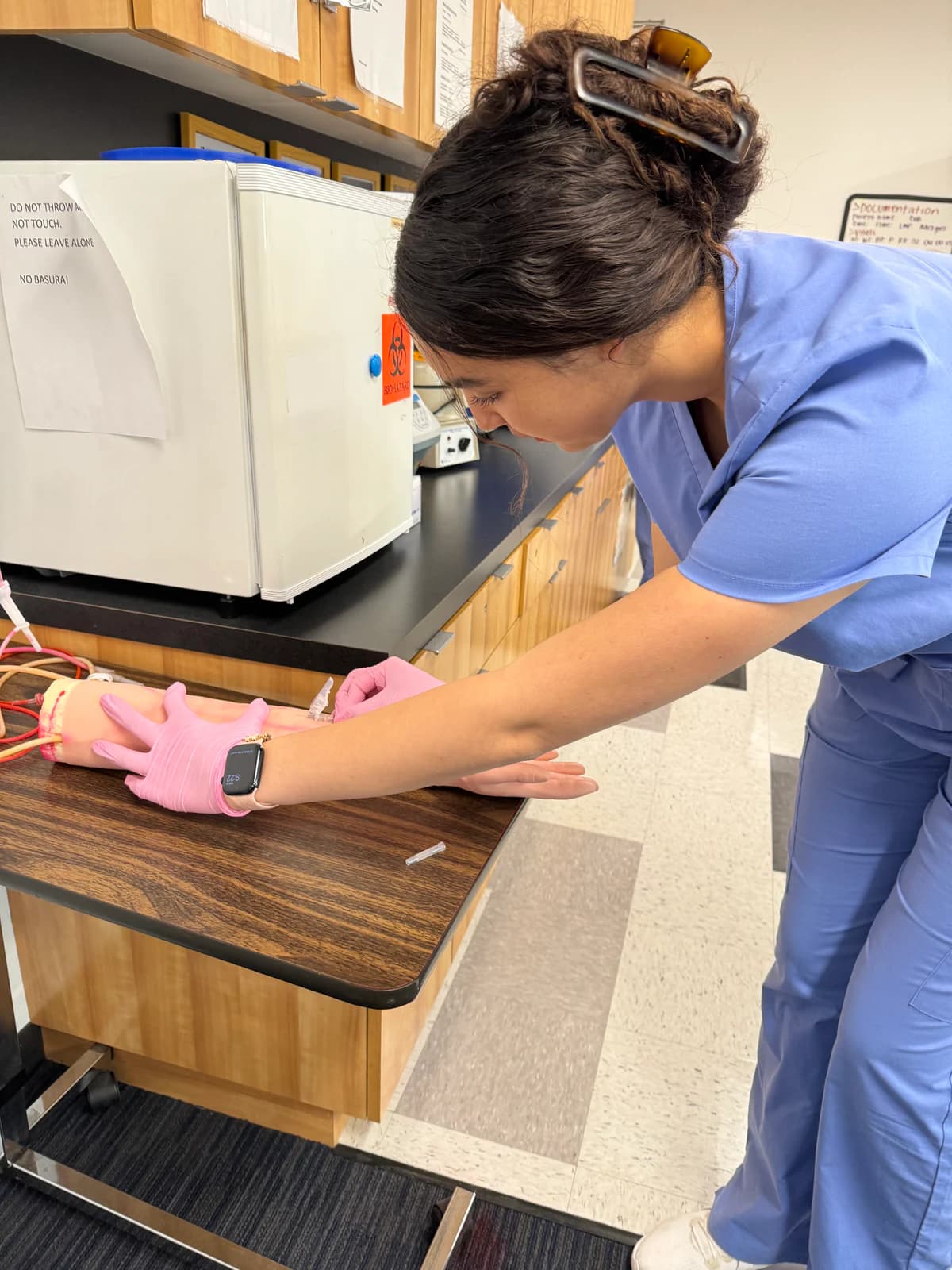 A Medical Assisting student practices an injection on an arm mannequin in a training lab.