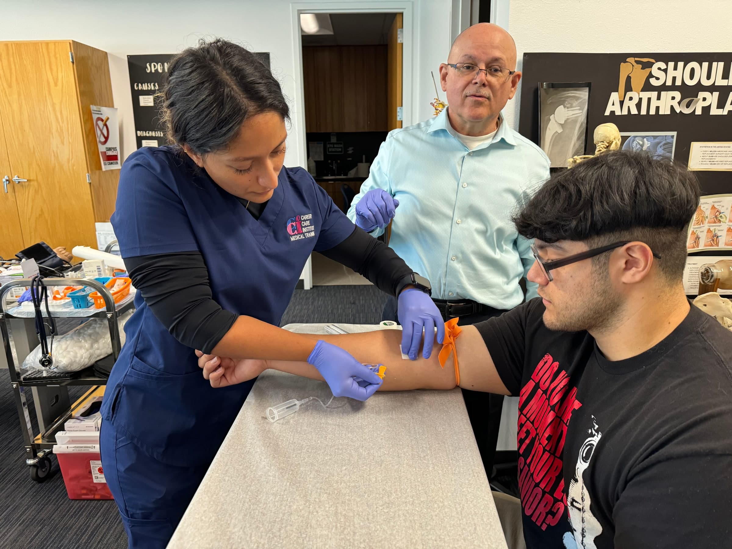 A CCI student practicing a blood draw under instructor supervision